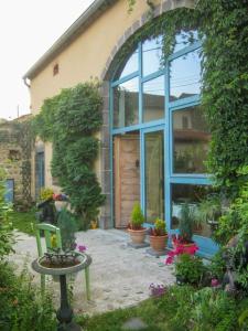 una casa con una ventana azul y algunas plantas en Chambres d'hôtes le Peyroux en Montcel