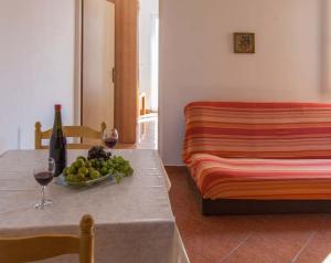 a table with a bowl of fruit and wine glasses at Apartmani Mudronja in Murter