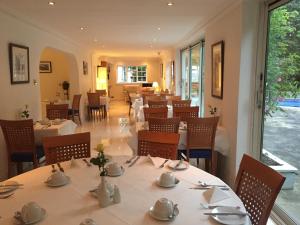 a restaurant with white tables and chairs and windows at Norfolk House in Maidenhead