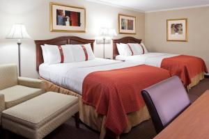 um quarto de hotel com duas camas e uma cadeira em Days Inn by Wyndham Warren em Warren