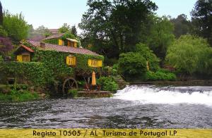 uma casa ao lado de um rio com uma cascata em Casas Da Azenha em Vila Nova de Cerveira