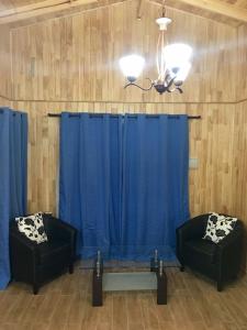 a room with two chairs and a blue curtain at Cabañas Alto Nativo in Chillán