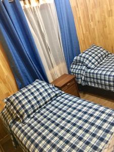 two beds in a room with blue curtains at Cabañas Alto Nativo in Chillán