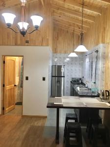 a kitchen with a table and a stove and a refrigerator at Cabañas Alto Nativo in Chillán