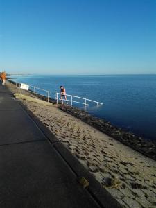 a man walking on a pier near the water at Am alten Siel in Wilhelmshaven