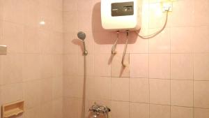 a bathroom with a shower with a phone on the wall at Puri Bebengan Bungalows in Ubud