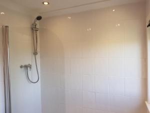 y baño con ducha y pared de azulejos blancos. en Workforce Property en Kirk of Shotts
