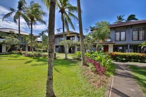 a house with palm trees in front of a yard at The Jayakarta Anyer in Anyer
