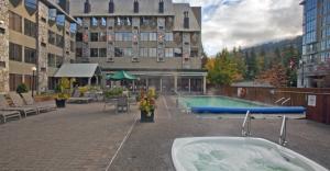 uma banheira sentada em frente a um edifício com uma piscina em Mountain Side Hotel Whistler by Executive em Whistler
