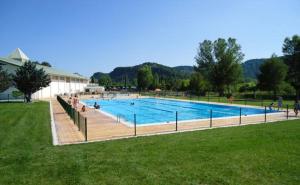 a large swimming pool with people sitting around it at Apartamento Sallan Ainsa Ordesa Zona Zero in Aínsa