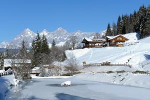 a house on a snow covered hill with a river at Strickhof in Schladming
