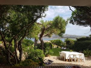 a table with white chairs and a view of the water at Giulianahouse in La Maddalena