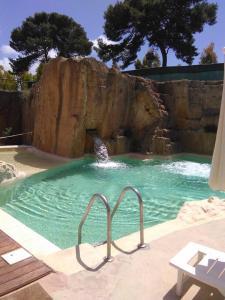 a swimming pool with a waterfall in a zoo at Residence Casale Verderame in Trapani