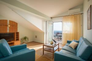 a living room with two blue couches and a large window at Apartments Cvjetni Dvori in Makarska