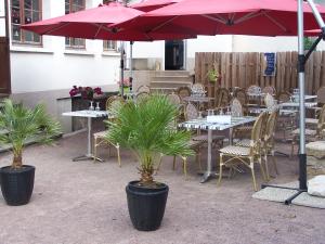 a patio with tables and chairs and a red umbrella at le lichou in Vallon-en-Sully