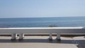 a white bench sitting next to the ocean at Hotel Forum in Costinesti
