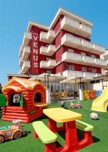 ein Gebäude mit einem Spielplatz mit Spielgeräten davor in der Unterkunft Hotel Venus in Riccione