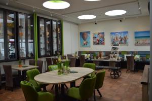 a dining room with tables and green chairs at Ferienapartments Cafe Stilbruch in Heimbach