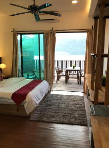 a bedroom with a bed and a balcony with a table at The Barat Perhentian in Perhentian Islands