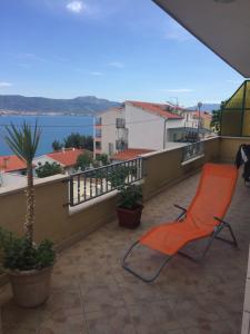 una silla naranja en un balcón con vistas al agua en Apartment Karmen, en Trogir