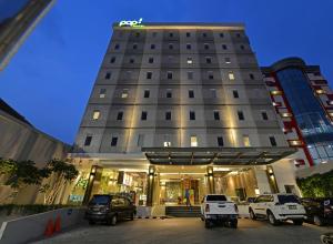 POP! Hotel Pasar Baru Jakarta في جاكرتا: مبنى فيه سيارات تقف امامه
