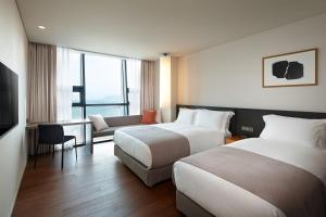 a hotel room with two beds and a television at Shilla Stay Haeundae in Busan
