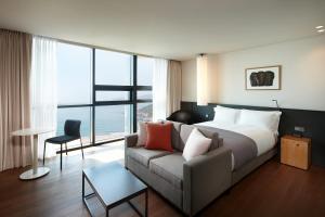 um quarto de hotel com uma cama e um sofá em Shilla Stay Haeundae em Busan