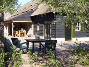 a patio with a table and chairs in front of a house at Boerderij & Bakhuis in Liempde