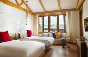 麗江市にあるホテル インディゴ リージャン エンシエント タウンのベッド2台とソファが備わるホテルルームです。
