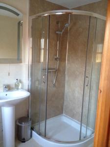 a shower with a glass door next to a sink at Chapel of Barras B&B in Stonehaven