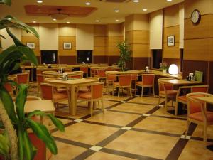 a restaurant with tables and chairs and a clock on the wall at Hotel Route-Inn Aso Kumamoto Airport Ekimae in Ozu