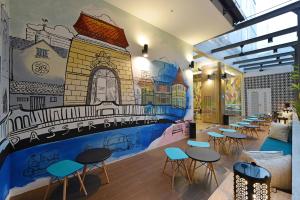 a room with tables and chairs and a mural on the wall at POP! Hotel Pasar Baru Jakarta in Jakarta