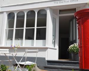 un ancien bureau de poste avec une chaise et un poteau rouge dans l'établissement The Old Post Office,Hassocks, à Ditchling