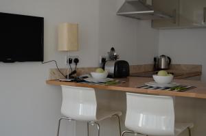 a kitchen with a counter and two white chairs at The Old Post Office,Hassocks in Ditchling