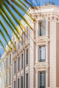 a large white building with windows and a palm tree at Residence Michel Ange in Cannes