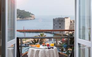 einen Tisch mit Speisen und Orangensaft auf dem Balkon in der Unterkunft Ragusina luxury apartments in Dubrovnik