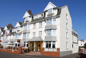 een groot wit gebouw op de hoek van een straat bij The Queens Hotel in Paignton