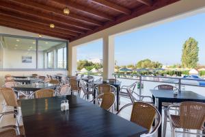 een restaurant met tafels en stoelen en een balkon bij Memphis Beach Hotel in Kolimbia