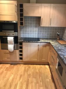 una cocina con armarios de madera y electrodomésticos de acero inoxidable en Hillford House, en Stirling