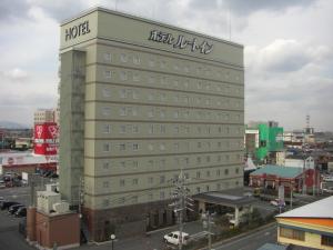 un grand bâtiment avec un panneau d'hôtel en haut dans l'établissement Hotel Route-Inn Matsusaka Ekihigashi, à Matsuzaka