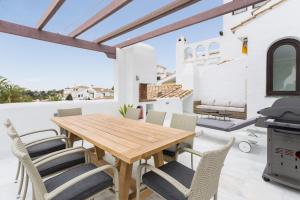 einen Holztisch und Stühle auf der Terrasse eines Hauses in der Unterkunft Aldea Blanca Puerto Banus in Marbella