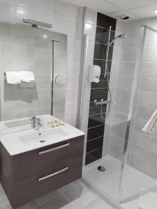 La salle de bains est pourvue d'une douche et d'un lavabo. dans l'établissement Logis Hôtel du Midi - Rodez Centre-Ville, à Rodez