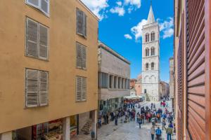 un grupo de personas caminando por una calle con una iglesia en Bell Apartment, en Zadar
