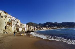 uma pessoa a caminhar numa praia perto do oceano em Cefalù cozy flat em Cefalù