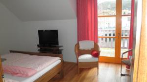 1 dormitorio con 1 cama, TV y silla en Penzion INspira, en Vranov nad Dyjí