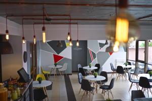 a restaurant with tables and chairs and a wall with geometric at Hotel Oxigen Petrosani in Petroşani