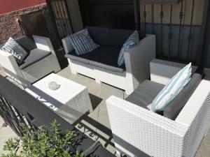 un patio con sillas blancas de mimbre y un sofá en Appartamento fronte mare en Moneglia