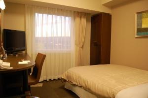 a hotel room with a bed and a desk and a window at Hotel Route-Inn Nabari in Nabari