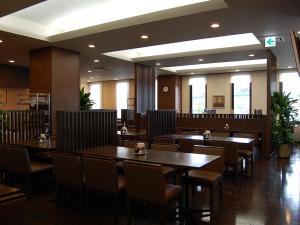 a dining room with tables and chairs in a restaurant at Hotel Route-Inn Nabari in Nabari