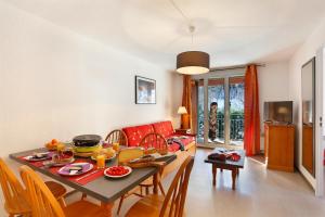 Résidence Goélia Les Grands Ax في آكس ليه تيرم: غرفة طعام وغرفة معيشة مع طاولة وكراسي